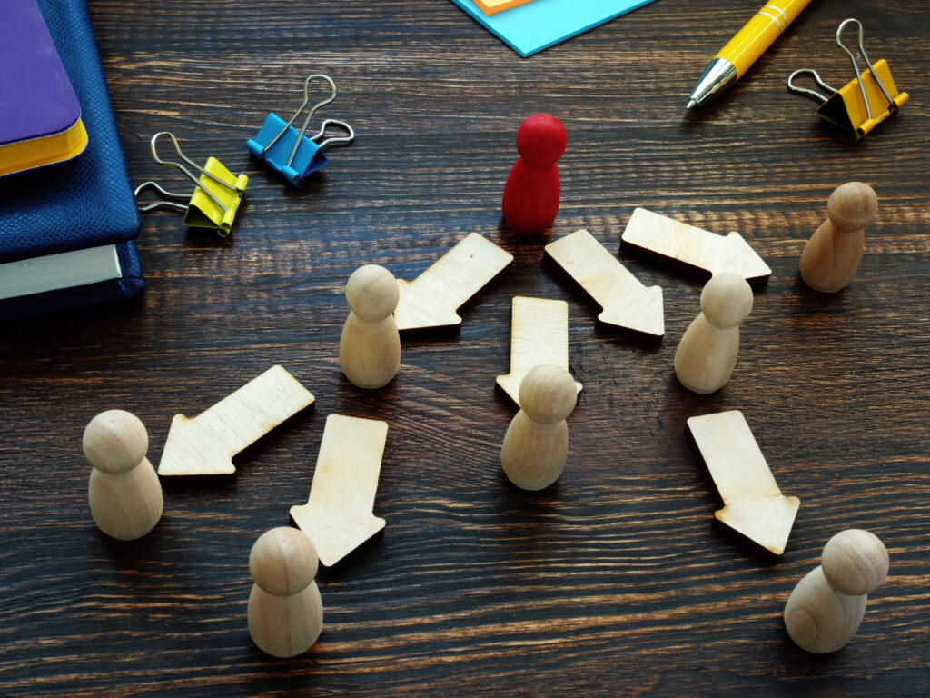 An image of a red wooden peg with game piece with arrows pointing towards other beige pieces.
