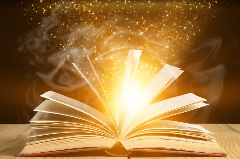 An image of a magical story book opening with lights and wispy clouds rising from the pages.
