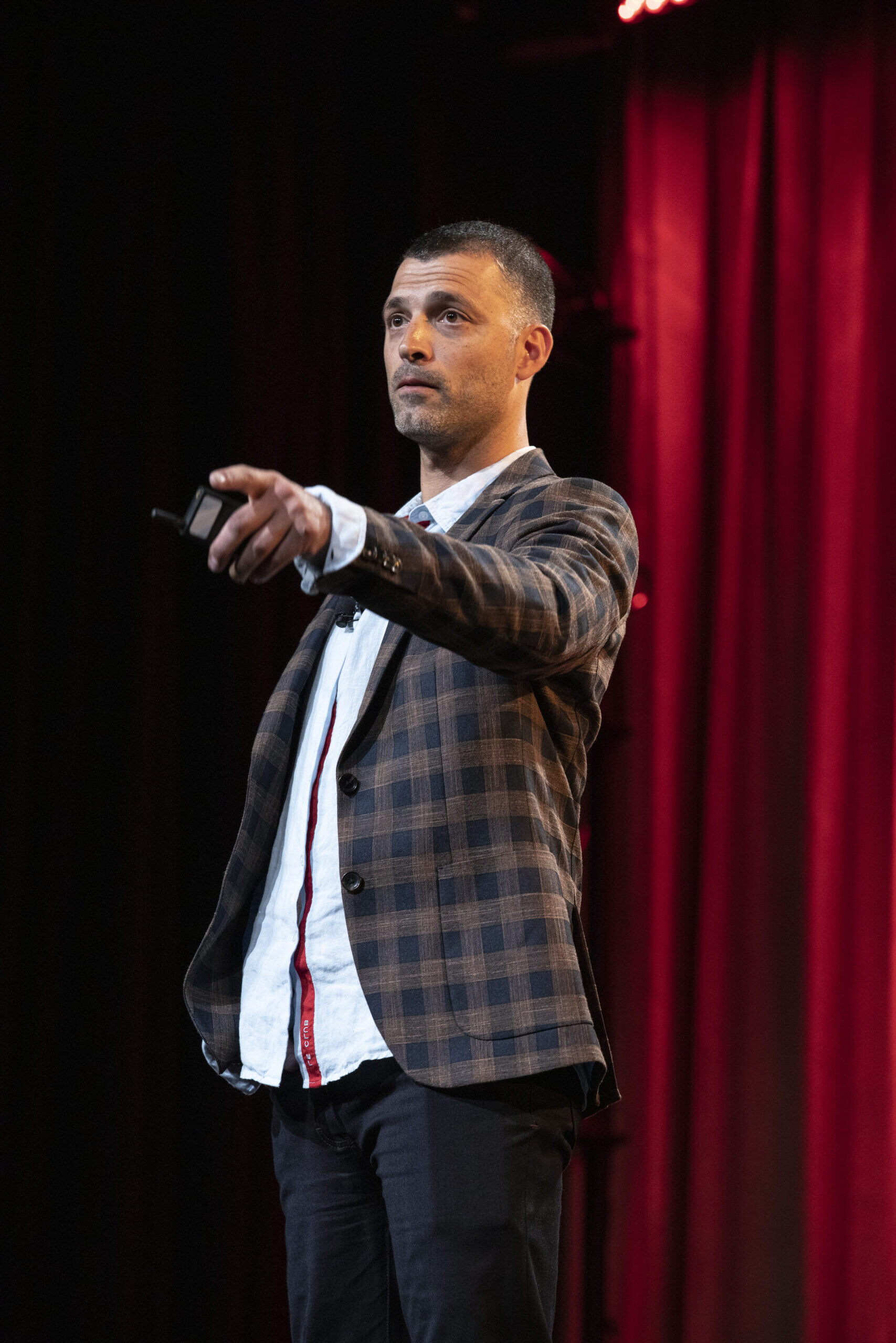 A photograph of Zack Viscomi speaking at SuccessSummit 2022 in front of a red curtain.